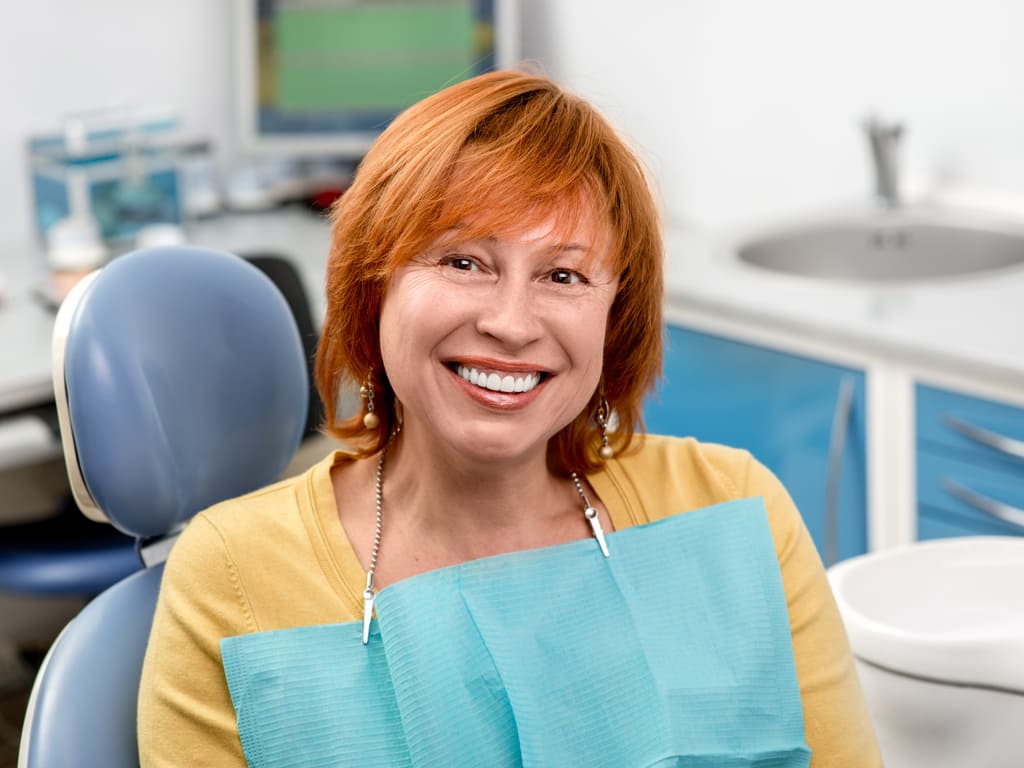 femme rousse souriante sur fauteuil de dentiste